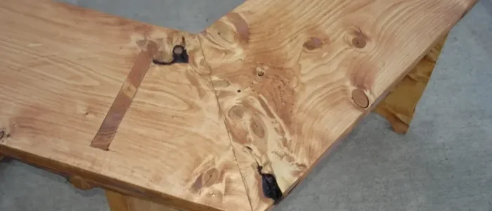 Custom L-shaped wood bench with a mitered corner, showing knots, natural grain, and butterfly key inlays